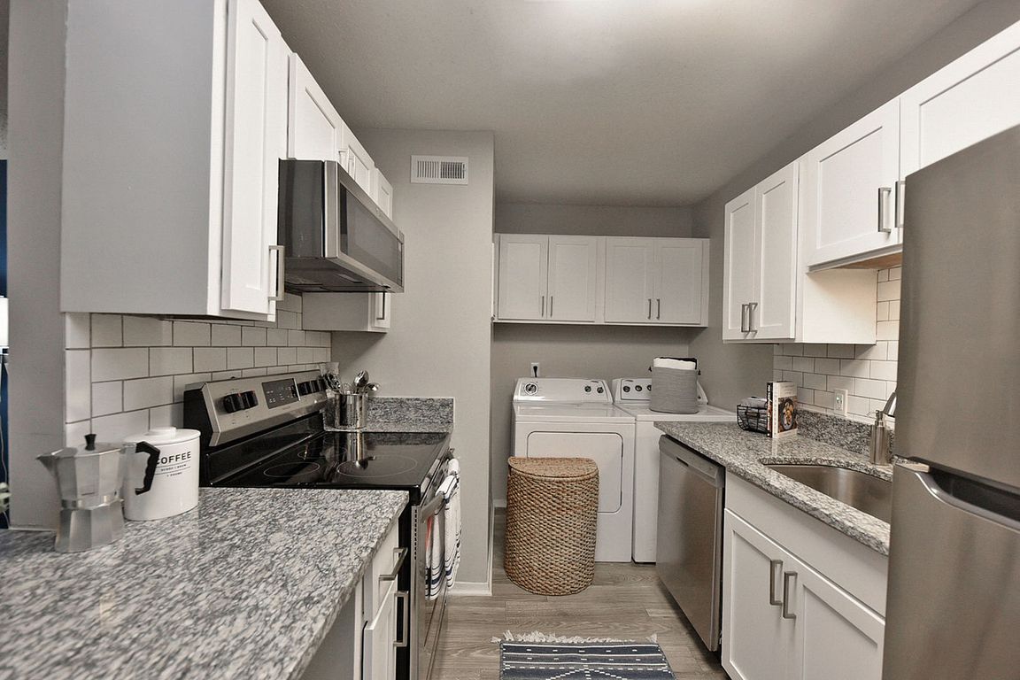 Kitchen with granite counters, washer & dryer, modern cabinetry, and stainless appliances