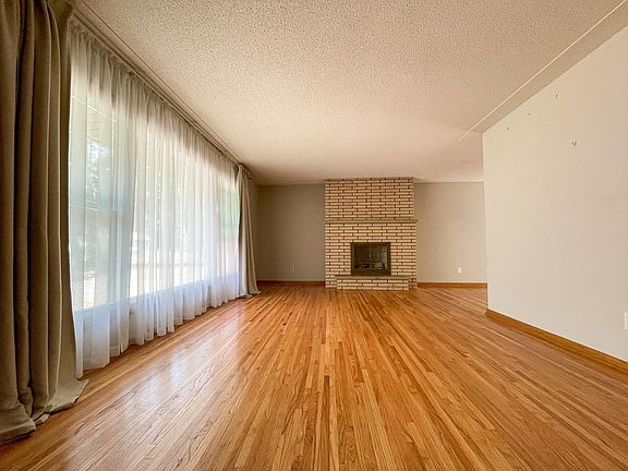Spacious light filled living room. Original brick and brass fireplace.