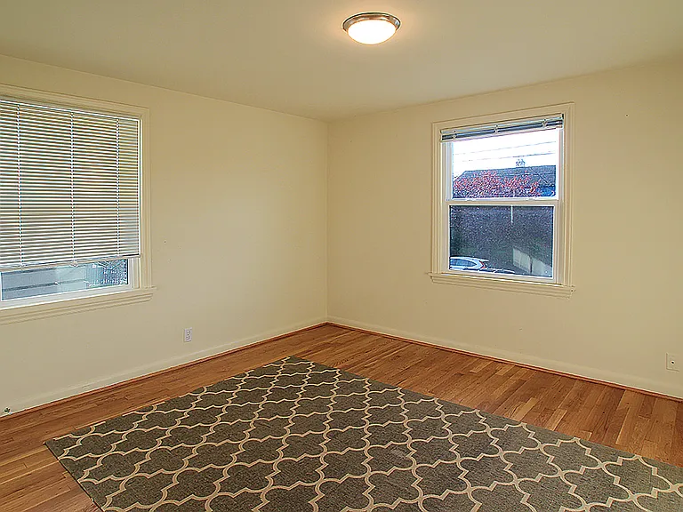 Mid-sized bedroom has windows facing South and East. Dimensions approximately 11.5 ft x 12 ft excluding closet.
