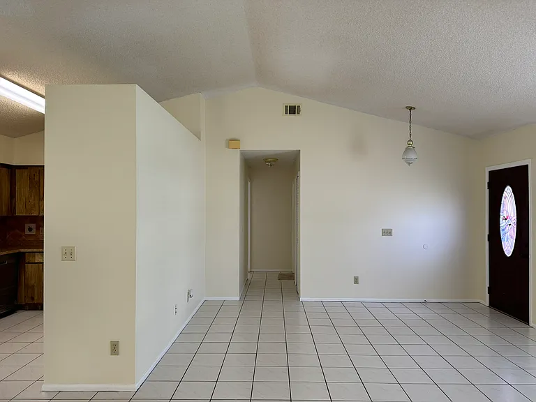 Kitchen (left), main living room (center), and front door (right)