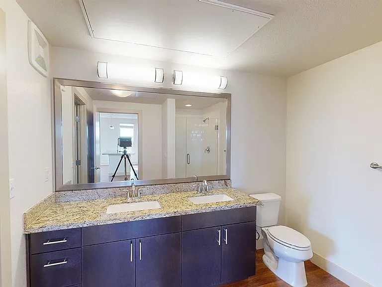 Apartment bathroom with wood-style flooring and double sinks.