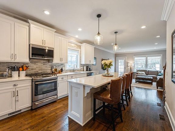 Sunny Kitchen offers large Center Island with Breakfast Bar, Stainless Steel Appliances, and Ample Countertops and Cabinets. Open to Eating Area and Family Room. Powder Room is Adjacent.