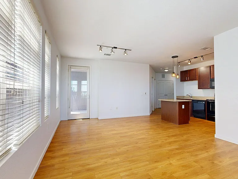 Apartment kitchen, dining, and living room with wood-style flooring.