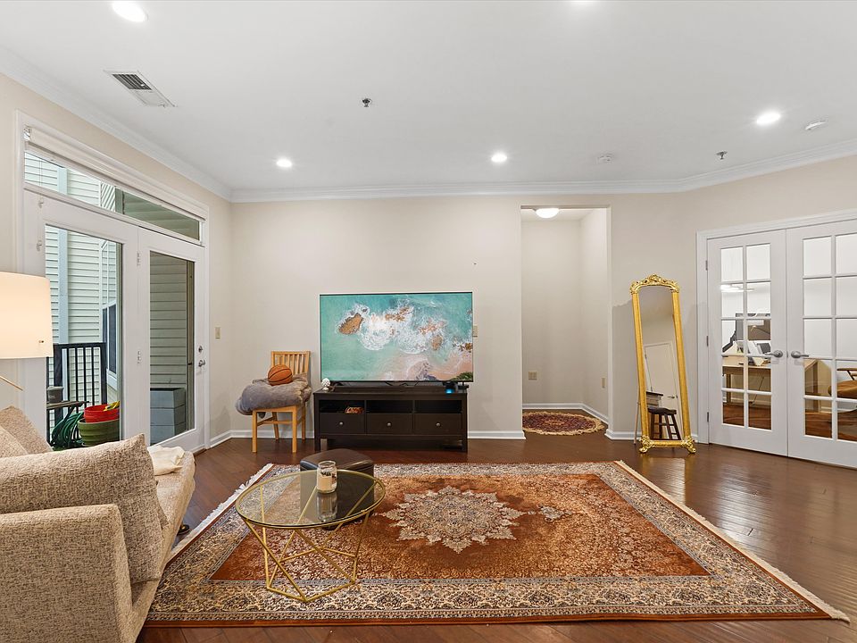 Living room: Open-concept living space flooded with natural light, featuring hardwood floors and seamless flow to the private patio