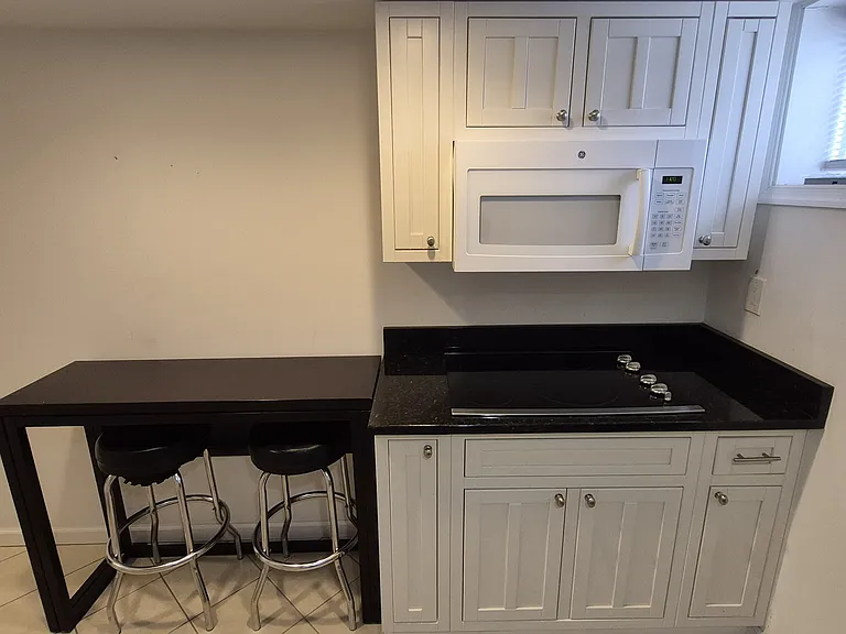 Compact kitchenette with cooktop, microwave, and dining nook _ efficient setup for daily living.