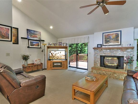 Large living room with gas fireplace, ceiling fan, and private deck.