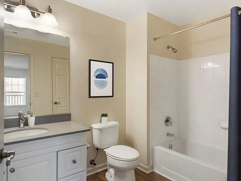 Phase I Renovated Package I apartment bath with grey quartz countertop, white cabinetry, and hard surface flooring