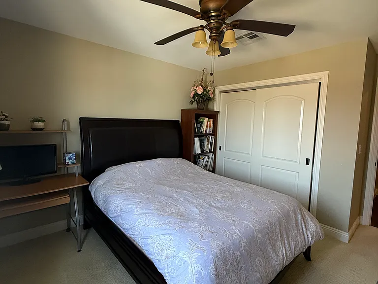 Bedroom 2 with ceiling fan, carpet, bed, desk and book shelf