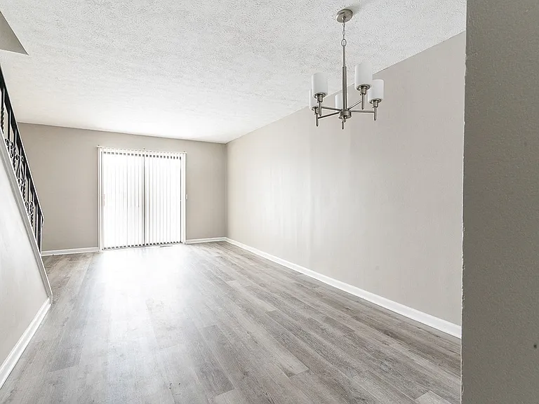 Interior of living/dining area with faux wood flooring viewed from the front entrance hall