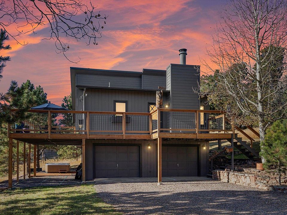 Driveway leads to two garages with room for one car and partially covered parking for more. Wrap around porch with upper and lower patio space.