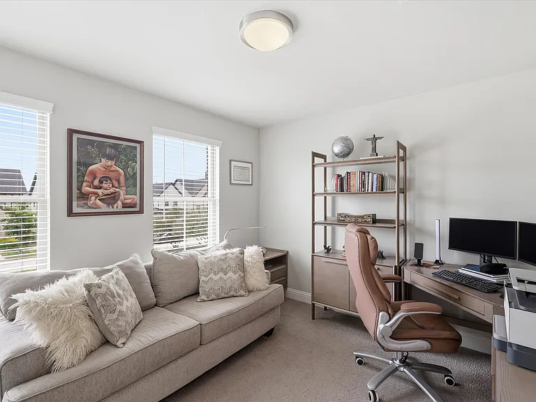 Secondary bedroom with two windows with horizontal blinds, neutral carpeting, light wall paint, and a flush mount ceiling light.