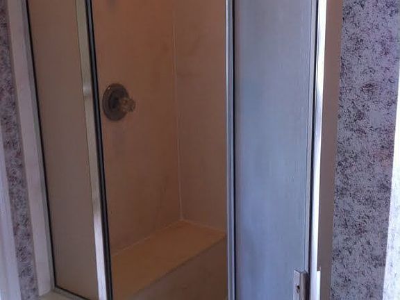 Shower is located behind the tub wall. Glass blocks behind tub.