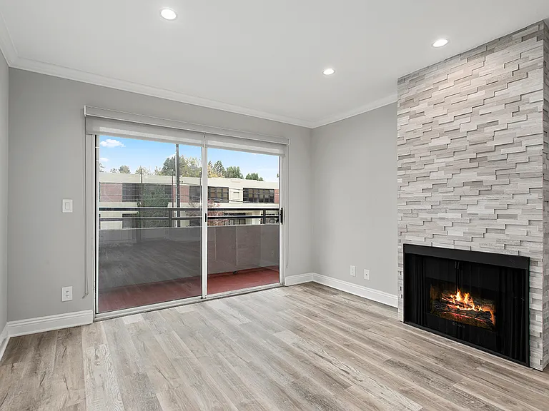 Cozy stone-walled fireplace in the living room with view of balcony.