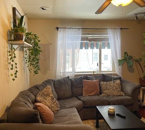 Enter Your LivingRoom with the Large Bright Front Window Looking back Outside, plus Furnished Sectional Sofa & Coffee Table