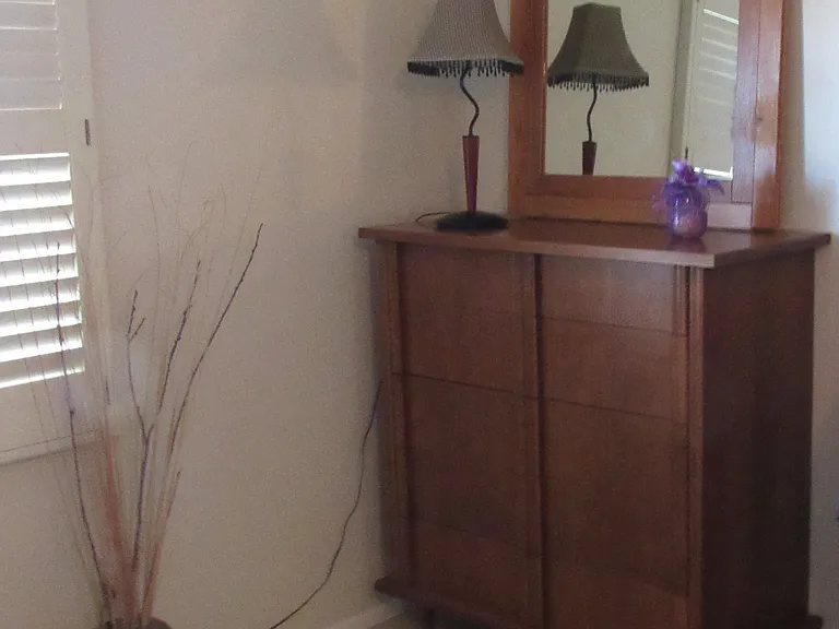 The dresser in the master bedroom with a mirror and a lamp.