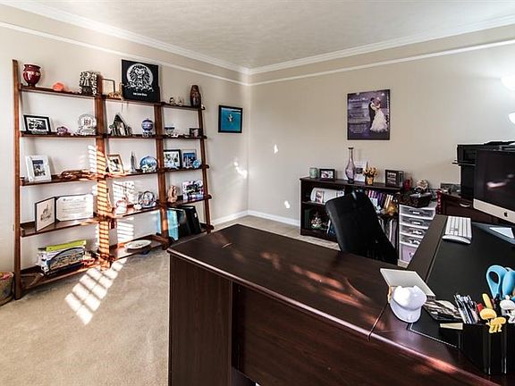 Living room 13 x 11 is being used as an office/den but offers crown molding and a neutral decor.