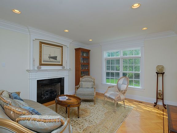 Formal living room with gas fireplace and hardwood floors in herringbone pattern with walnut inlay