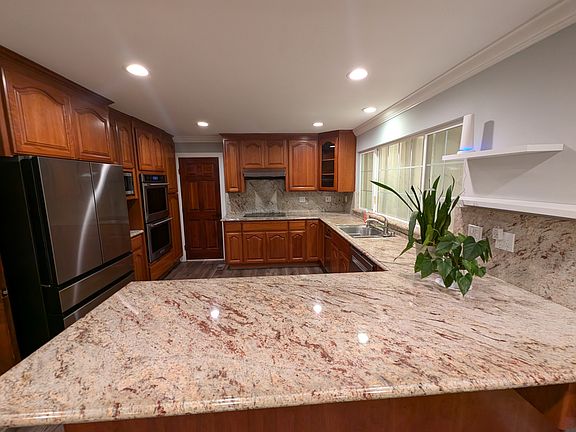 Elegant chef's kitchen with granite counters and backsplash. Stainless steel appliances: Newer refrigerator, Microwave Kitchenaid Double Convection Oven and Trash Compactor, Induction Cooktop, Bosch Dishwasher. Bright recessed lighting.