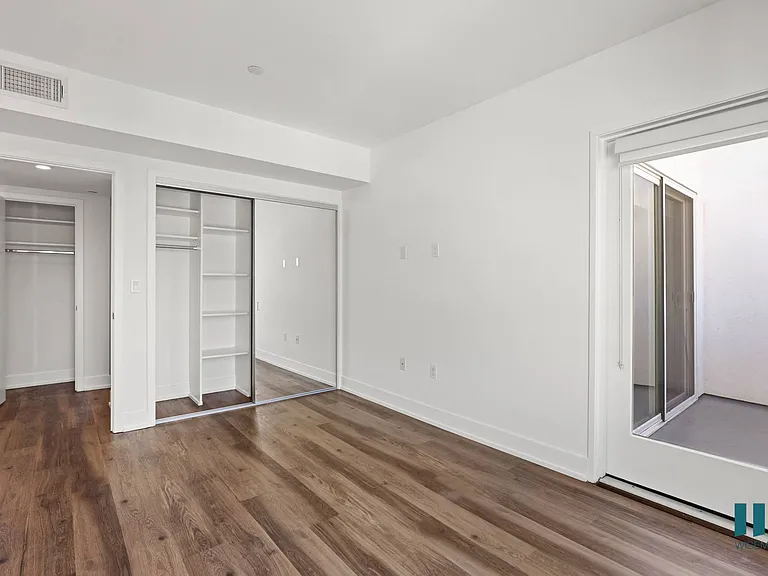 Bedroom with Mirrored Closet with Shelving, Vinyl Flooring, and Spacious Patio