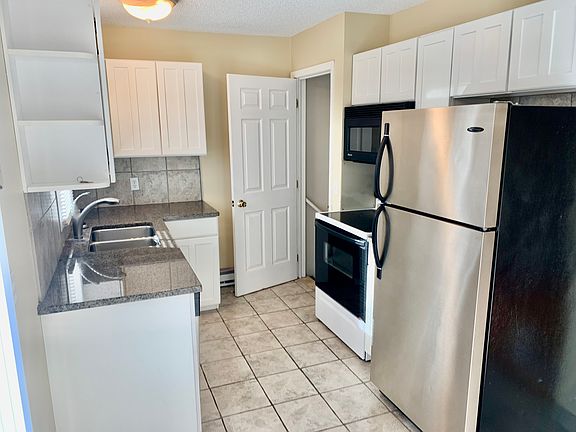 Kitchen with granite countertops, ceramic tile.