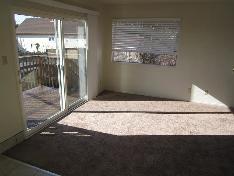 Patio door to backyard balcony with steps leading to two carport tenant spaces and spacious locked storage room