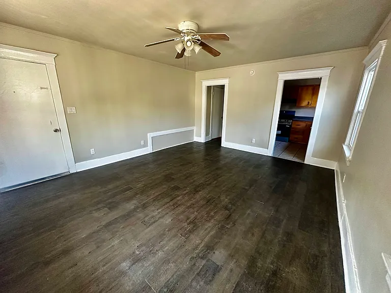 Huge living room with lots of natural lights, windows, and ceiling fan.