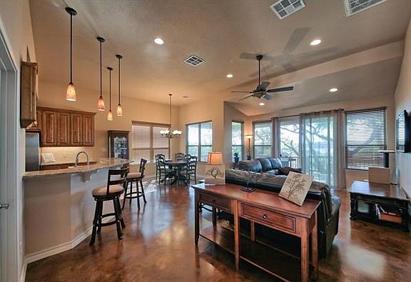 The open concept living areas flow from kitchen to dining and living areas, with access to covered rear balcony and outdoor dining spaces.