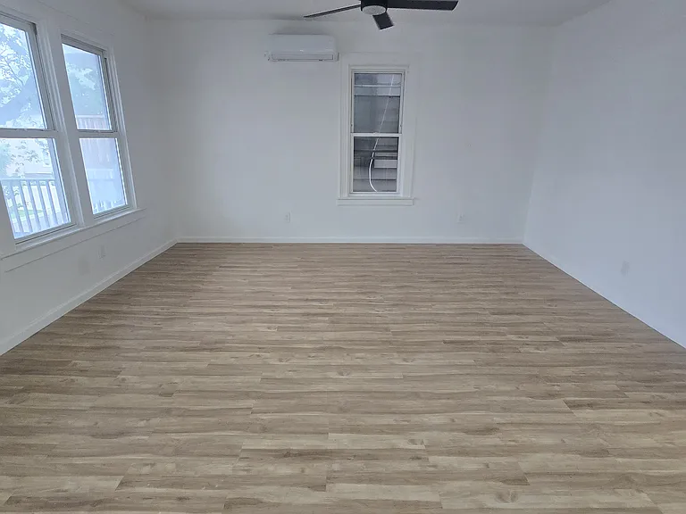 Open floor plan living room with ductless heating/cooling and ceiling fan.