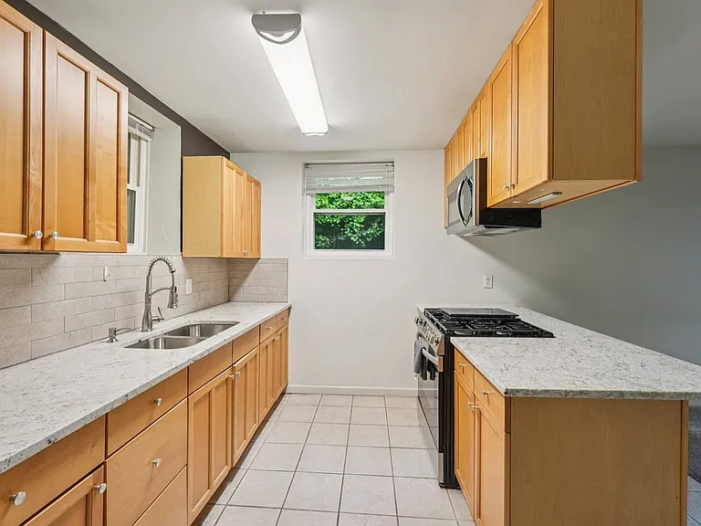 This inviting kitchenette feels like a practical little storybook corner, offering generous storage, bar seating, and a bright layout perfect for simple meals and morning coffee.