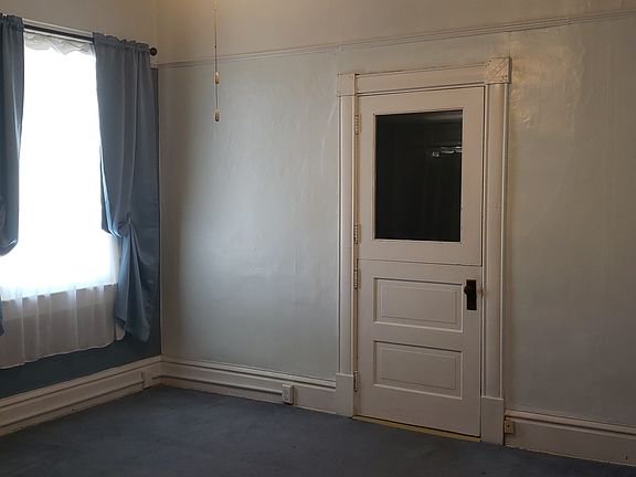 The spacious living room is 15 x 17. painted in Ice Blue, with the windowed wall in Norwegian Blue. The window features silky dark blue thermal drapes over a soft white sheer.