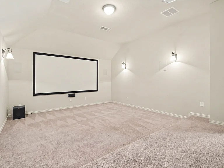 Dedicated media room featuring a large projection screen and wall-mounted sconce lighting