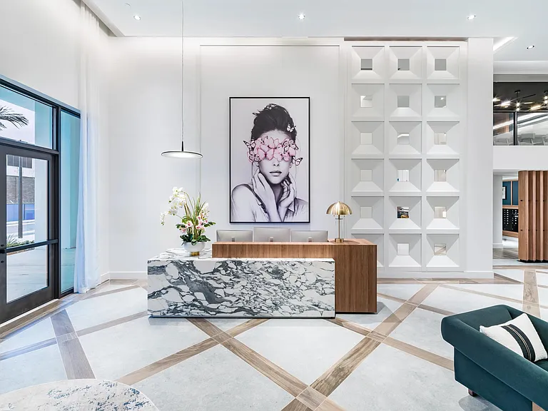 A sculptural arrival moment at Modera Aventura, pairing marble, warm wood, and curated art for a striking first impression rooted in coastal sophistication.