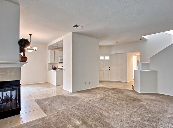 Another view of the living room with 3-sided fireplace, dining room and entry