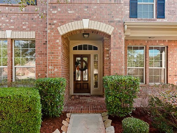 Lush landscape and flagstone lined walkway invite you to patio and lead glass front door.