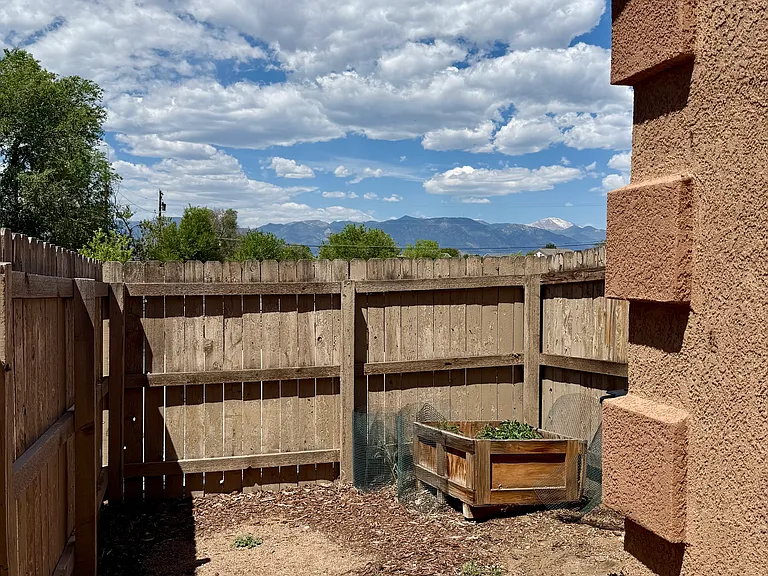 Private fenced outdoor space with a raised garden bed and Pikes Peak views.