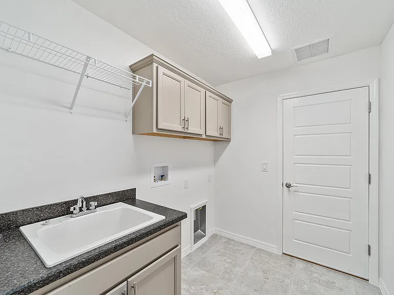 Well-organized laundry room with utility sink, cabinets, and storage racks