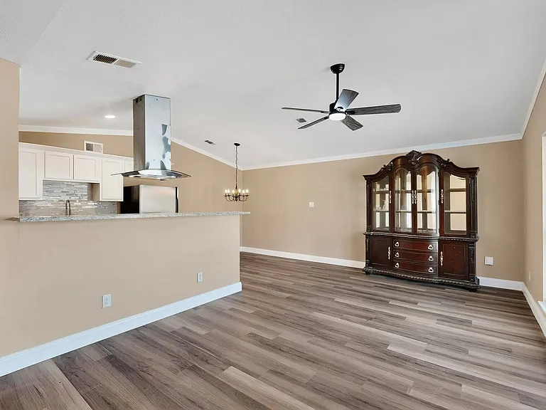 Unfurnished living room featuring light wood finished floors, ornamental molding, a chandelier, and ceiling fan