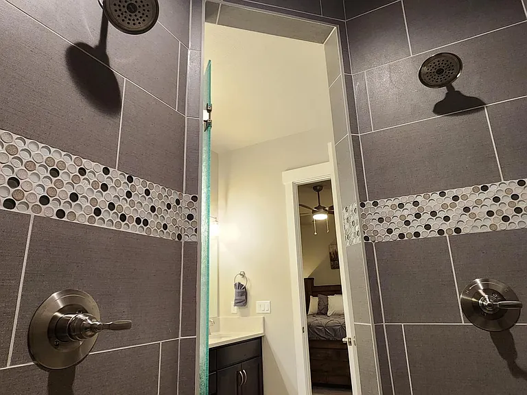 Walk-in shower with dual shower-heads, sitting bench and upgraded tile floor