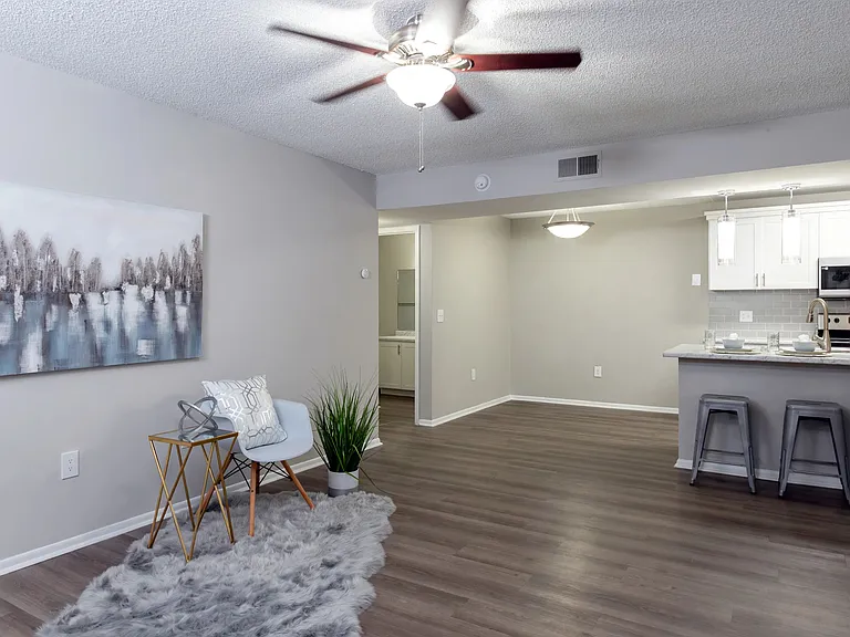 Spacious living rooms, where wood-style floors meet dancing ceiling fans in a cozy embrace.
