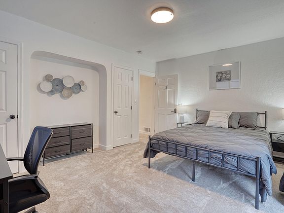 Large room with two closets, queen size bed with bedding as well as a desk and chair.