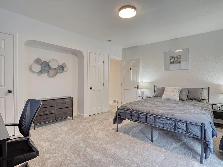 Large room with two closets, queen size bed with bedding as well as a desk and chair.