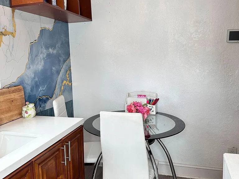 Compact dining nook with a round glass table, seating for two, and adjacent counter space for easy everyday meals.