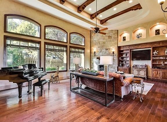 Light and airy open concept living room with soaring ceilings and high end custom finishes (hand scraped walnut flooring, dry stacked stone and plaster walls).