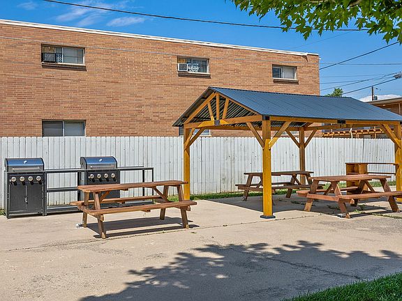 Charming outdoor picnic area with wooden tables and a stylish gazebo, perfect for gatherings and BBQs, set against a sunny backdrop.