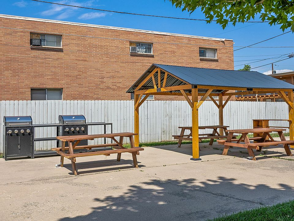 Charming outdoor picnic area with wooden tables and a stylish gazebo, perfect for gatherings and BBQs, set against a sunny backdrop.