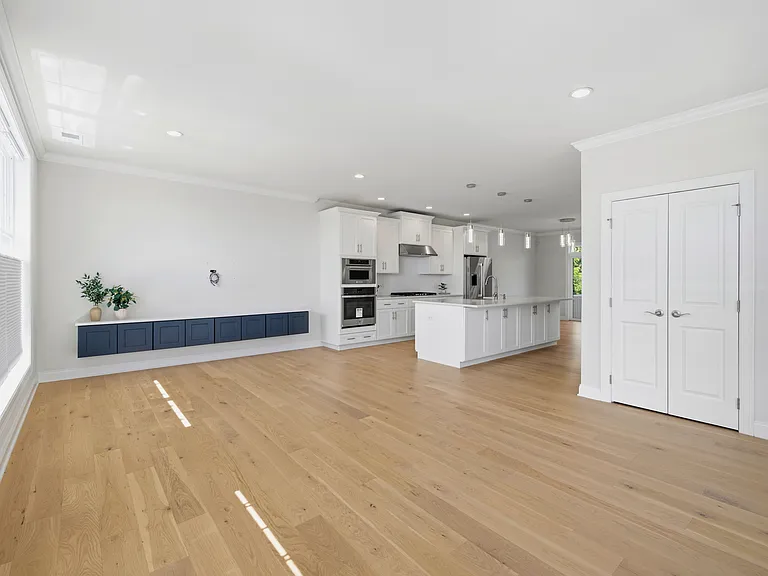 Airy, spacious living room features gorgeous natural light, custom built-in cabinetry, and storage closet.