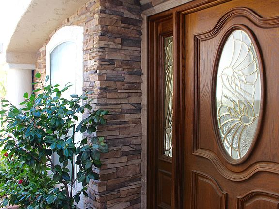 Custom stone and lush greens surround the front entry