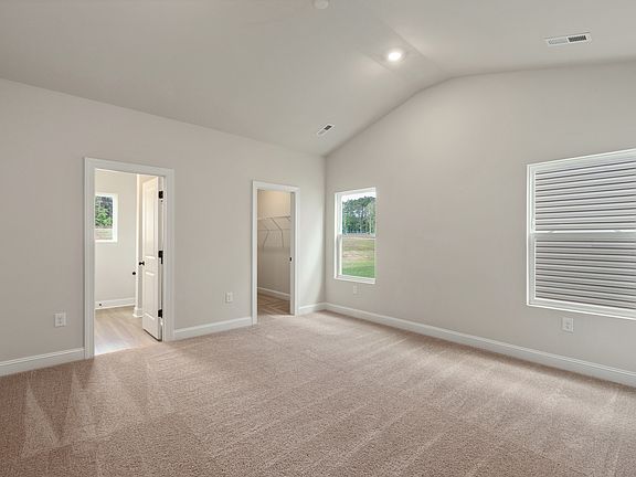 This master bedroom features a vaulted ceiling and plenty of natural light
