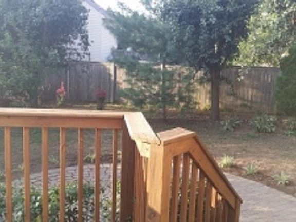 Shaded back yard with a deck and screened in porch.