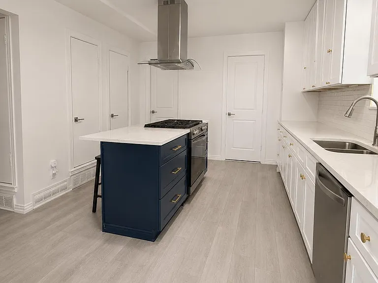 Open kitchen with long counters, ample cabinetry, and a large island with gas range and vent hood for easy meal prep.